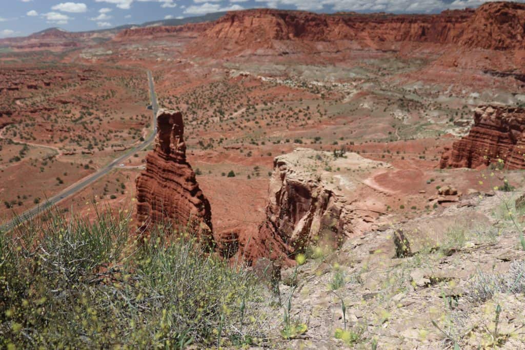 Chimney Rock formation in Capitol Reef National Park, Utah, rising from red sandstone cliffs with Highway 24 visible in the distance.