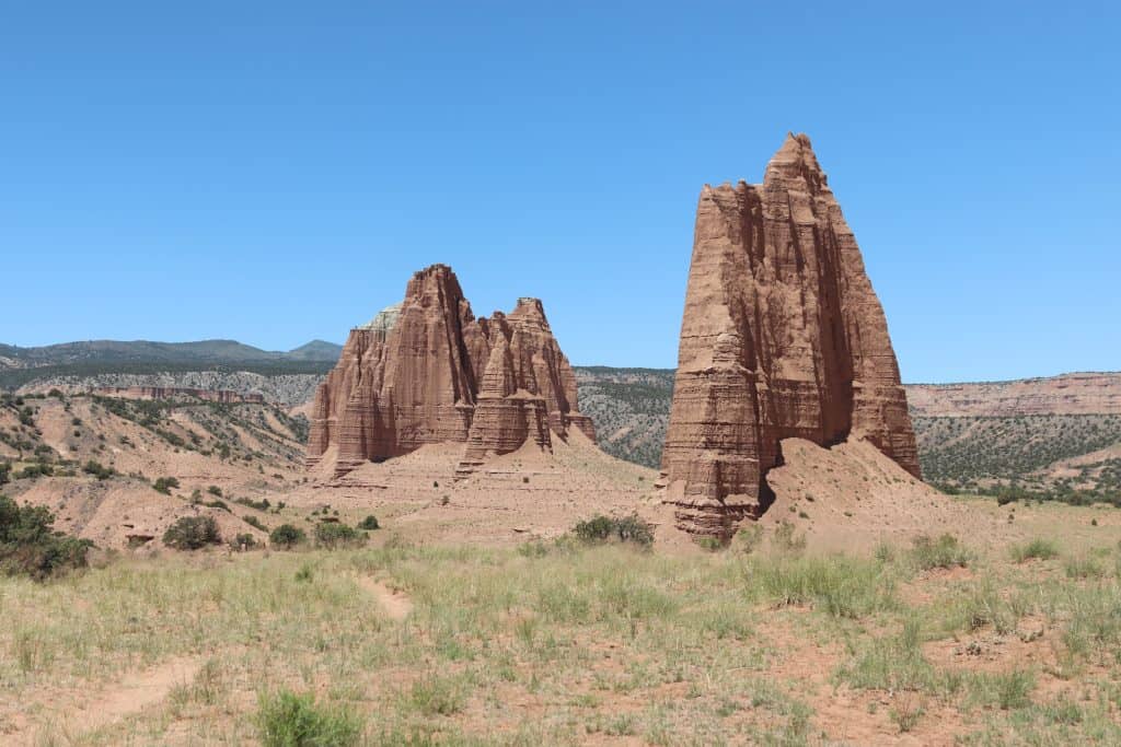 Massive sandstone monoliths known as the Cathedrals in Capitol Reef National Park’s Cathedral Valley, Utah, rising from the desert floor under a clear blue sky.